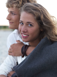 Young couple wrapped in blankets on beach. Date : 2008