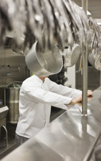 Chef leaning on shelf in commercial kitchen. Date : 2008