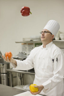 Chef juggling assorted peppers. Date : 2008