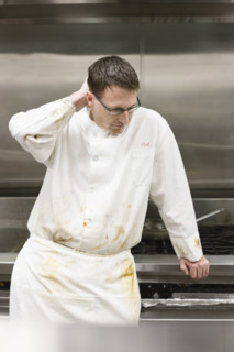 Tired chef leaning against stove. Date : 2008