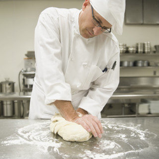 Baker kneading bread dough. Date : 2008