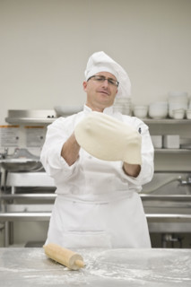 Chef stretching pizza dough. Date : 2008