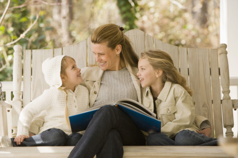 Mother reading to daughters on porch swing. Date : 2008