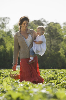 Mother and baby daughter picking strawberries. Date : 2008