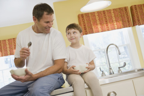 Father and son eating breakfast on kitchen counter. Date : 2008