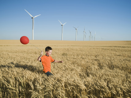 Boy running with balloon on wind farm. Date : 2008