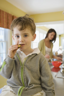 Boy eating cookie on kitchen counter. Date : 2008