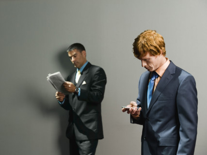 Businessmen holding newspaper and cell phone. Date : 2008