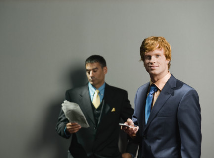 Businessmen holding newspaper and cell phone. Date : 2008