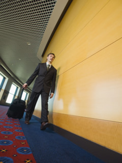 Businessman pulling suitcase in office corridor. Date : 2008