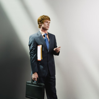 Businessman holding cell phone, files and briefcase. Date : 2008