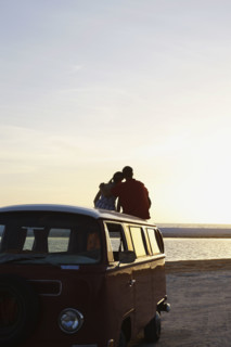 Couple watching ocean sunset from top of van. Date : 2008