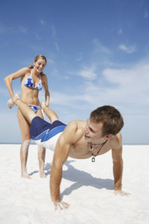 Teenage girl pushing boyfriend on beach. Date : 2008