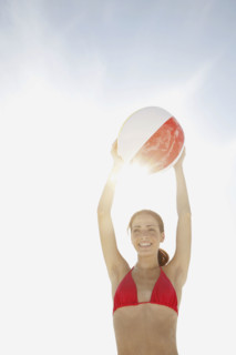 Young woman holding beach ball above head. Date : 2008
