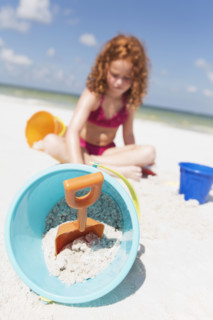 Girl digging in sand on beach. Date : 2008