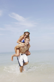 Young man carrying girlfriend on back in ocean. Date : 2008