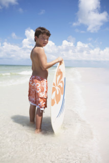 Boy holding skimboard in ocean. Date : 2008