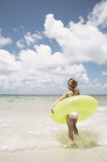 Girl carrying inflatable ring into ocean. Date : 2008