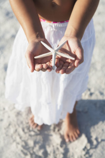 Girl on beach holding delicate starfish. Date : 2008