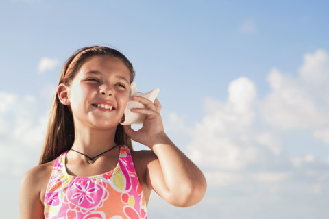 Girl holding conch shell to ear. Date : 2008