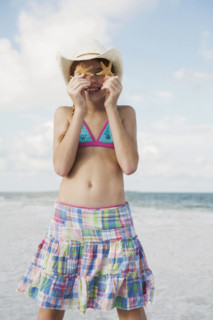 Girl on beach holding starfish. Date : 2008
