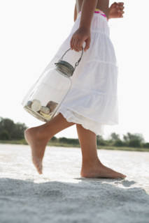 Girl on beach carrying jar of shells. Date : 2008