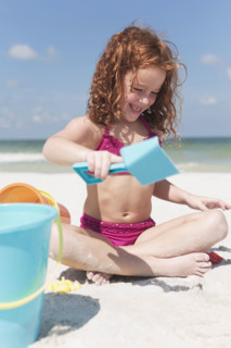 Girl digging in sand on beach. Date : 2008