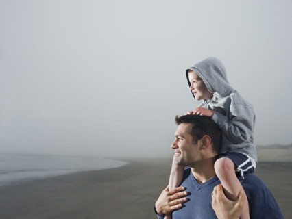 Father carrying son on shoulders on beach. Date : 2008