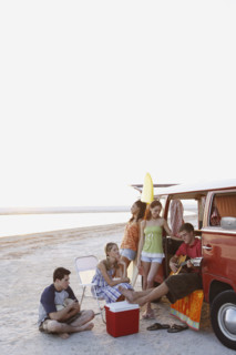 Friends lounging around van on beach. Date : 2008