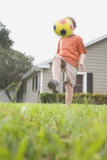 Boy in backyard kicking soccer ball. Date : 2008