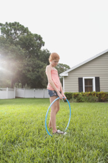 Girl standing in backyard with hula hoop. Date : 2008