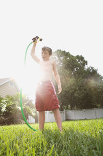 Boy spraying himself with hose in backyard. Date : 2008