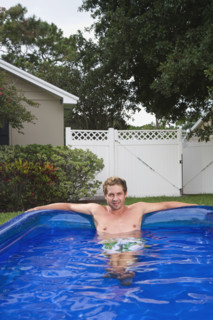 Portrait of man soaking in inflatable swimming pool. Date : 2008