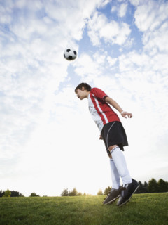 Boy in uniform bouncing soccer ball off head. Date : 2008