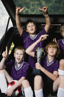 Boys soccer team holding trophy in back of car. Date : 2008