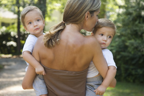 Mother carrying twin toddler sons. Date : 2008