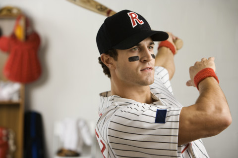 Baseball player practicing swing in locker room. Date: 2008