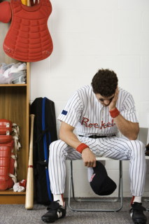 Baseball player sitting with head in hands in locker room. Date : 2008