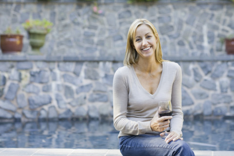 Woman with wine glass sitting on edge of swimming pool. Date : 2008