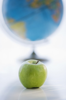 Green apple with globe in background.
