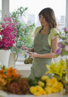 Florist holding clipboard and looking at flowers.