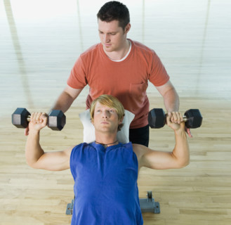Personal trainer spotting man with dumbbells. Date : 2008