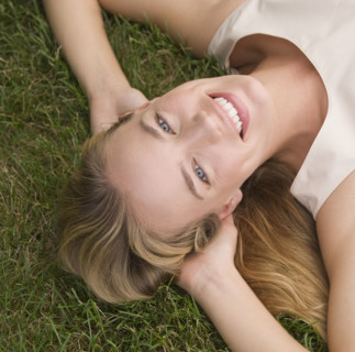Woman laying in grass with hands behind head.