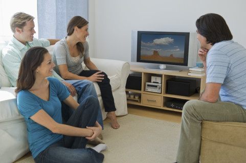 Couples watching television in living room.