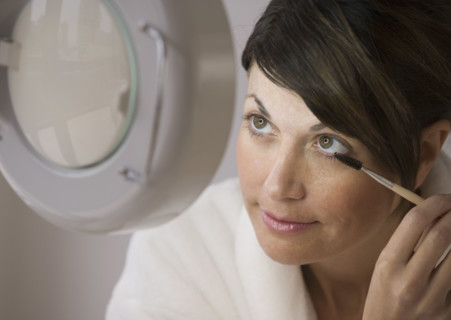 Woman applying makeup vanity mirror.