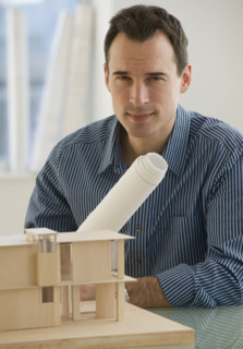 Portrait of architect with blueprints and building model.