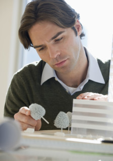 Close up of architect working on building model.