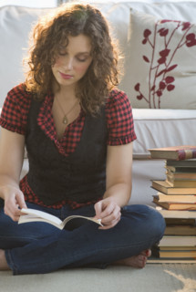 Woman reading book on living room floor.