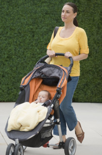Mother walking baby son in stroller.