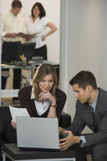Businessman and businesswoman using laptop.